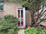 The memorial booth nestled among trees, garden plants and red mushroom sculptures