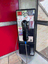 A close view of the vintage black payphone against the booth’s red interior