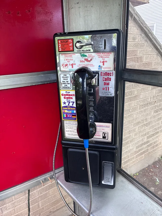 A close view of the vintage black payphone against the booth’s red interior